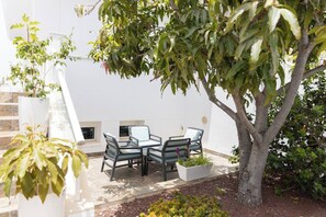An outdoor seating area with a table and chairs, surrounded by potted plants and a tree. - 6-Bedroom Luxury Villa | Pool, Hot Tub, Movie Theater & Pool Table (Adeje)