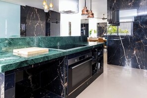 A modern kitchen with a marble countertop, built-in oven, and pendant lighting. - 6-Bedroom Luxury Villa | Pool, Hot Tub, Movie Theater & Pool Table (Adeje)