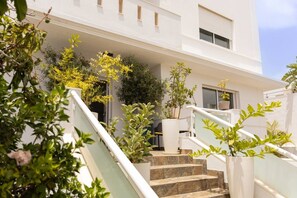 A building with a white exterior, a staircase leading to the entrance, and various plants around the area. - 6-Bedroom Luxury Villa | Pool, Hot Tub, Movie Theater & Pool Table (Adeje)