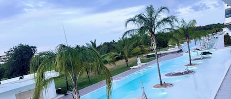 A pool area with multiple lanes, palm trees, and a clear sky.