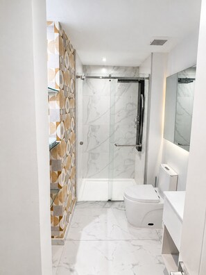 Ein modernes Badezimmer mit einer Duschkabine aus Glas, einer Toilette und einem Waschbecken.