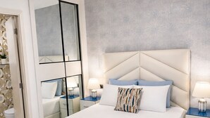 A modern bedroom with a large bed, a ceiling fan, and a bathroom with a toilet and sink. - Apartamento con balcon en Cana Bay Punta Cana (Punta Cana 23000)