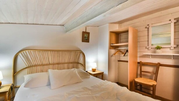 A bedroom with a bed, a chair, a nightstand, a lamp, and a shelf with a mirror. - Heart of Les Gets - Apartment for 6 people - 3 bedrooms (Les Gets)