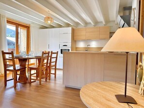 Eine moderne Küche mit Holzschränken, einer zentralen Kochinsel und einem Essbereich mit rundem Tisch und Stühlen.