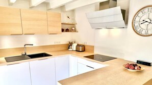A modern kitchen with white cabinetry, a wooden countertop, a built-in oven, and a wall-mounted clock. - Heart of Les Gets - Apartment for 6 people - 3 bedrooms (Les Gets)