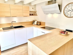 Eine moderne Küche mit weißen Schränken, einer Holz Arbeitsplatte, einem eingebauten Backofen und einer Wanduhr.