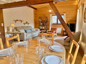 A dining area with a wooden table set for a meal, surrounded by chairs.