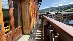 A wooden building with a balcony overlooking a village and hills. - Heart of Les Gets - Apartment for 6 people - 3 bedrooms (Les Gets)