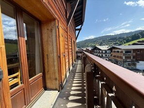 Ein Holzbalkon bietet Blick auf ein Dorf und Hügel.