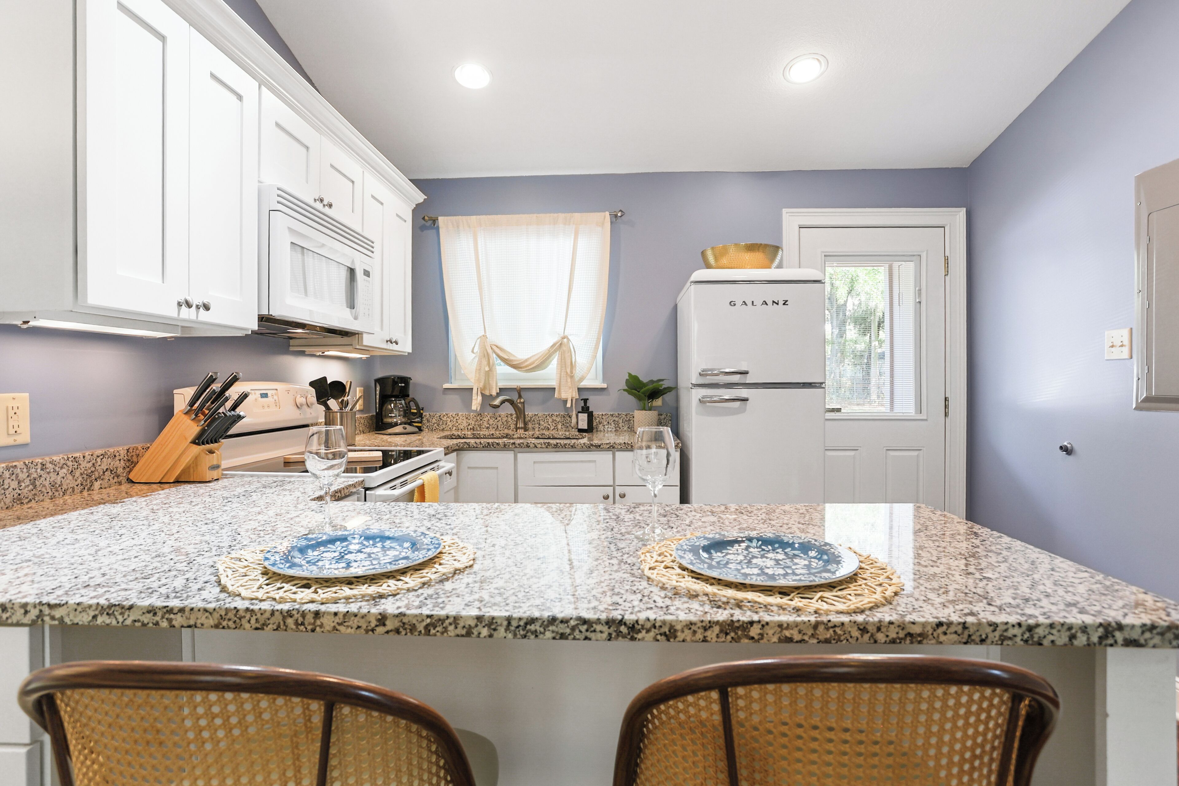 A kitchen with white cabinets, a double sink, and a Galanz refrigerator.