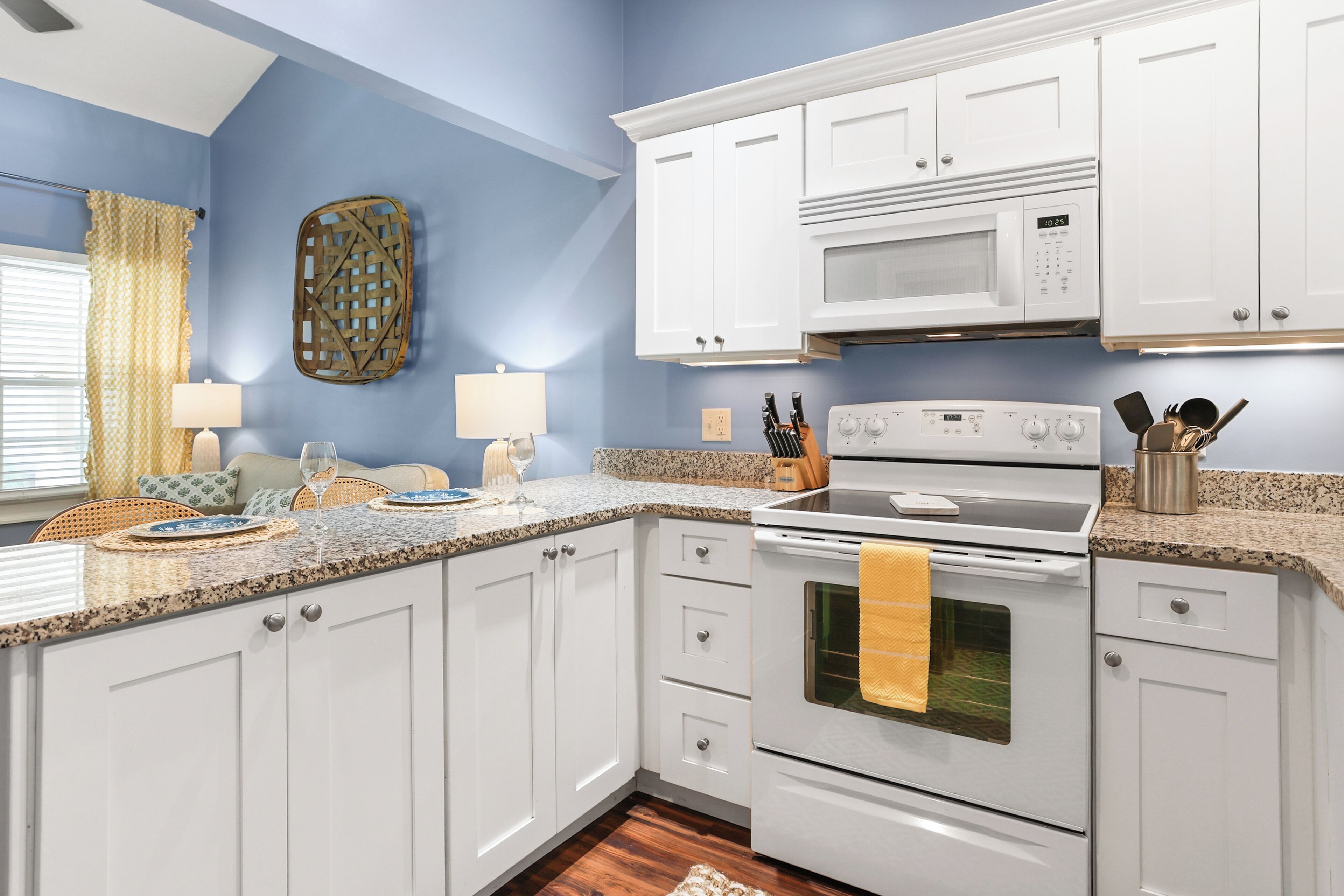 A kitchen with white cabinets, a microwave, an oven, and a granite countertop.