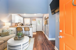 A compact kitchen with white cabinets, a refrigerator, and a dining area with a round table and two chairs. - Cozy One-Bedroom • Full Kitchen • Renovated 2026 * Historic Grounds (Savannah)