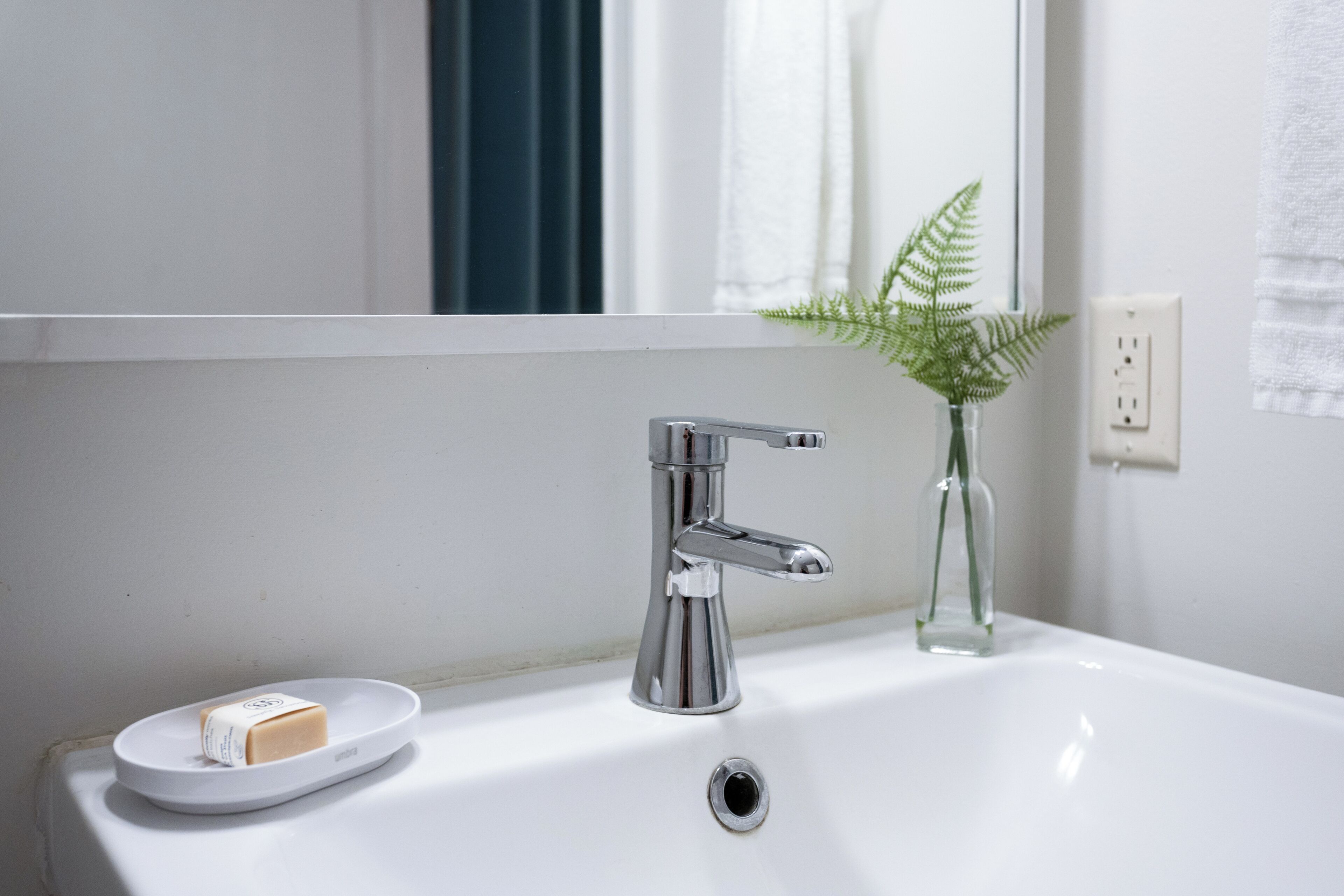 Ein Badezimmer mit Waschbecken, Armatur aus Chrom und einer Seifenschale mit Seife.