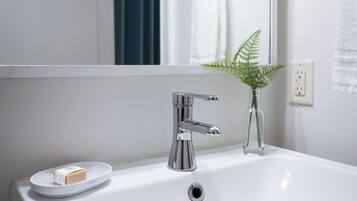 Ein Badezimmer mit Waschbecken, Armatur aus Chrom und einer Seifenschale mit Seife.