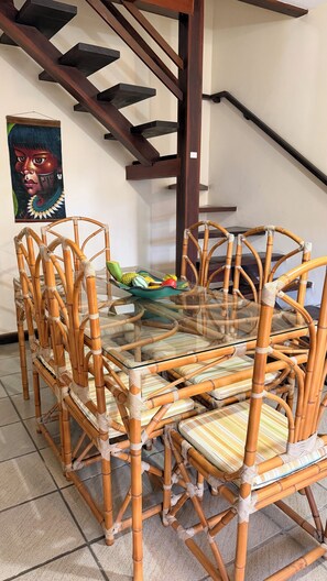 A dining area with a glass-top table surrounded by wicker chairs. - Premium House | 250m Taperapuan Beach | Axé Moi (Porto Seguro)