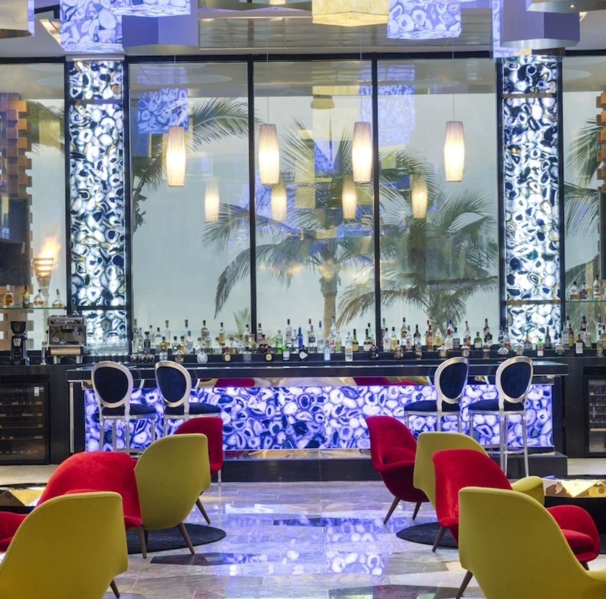 A bar area with a counter, chairs, and a decorative wall with a pattern.