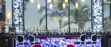 A bar area with a counter, chairs, and a decorative wall with a pattern.