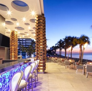 An outdoor bar area with seating, a view of the ocean, and a modern architectural design with circular light fixtures. - Cozy Studio, 1-bedroom, in welcoming Cabo San Lucas with a beautiful view. (Cabo San Lucas)