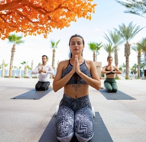 A person in a yoga pose on a mat outdoors with palm trees and a clear sky in the background. - Cozy Studio, 1-bedroom, in welcoming Cabo San Lucas with a beautiful view. (Cabo San Lucas)