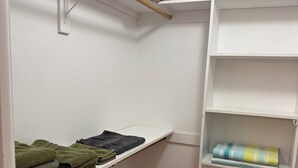 Ein Schrank mit Regalen und Kleiderstange, gefüllt mit gefalteten Handtüchern und einer zusammenrollten Decke.