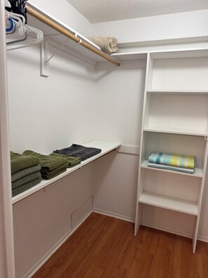 Ein Schrank mit Regalen und Kleiderstange, gefüllt mit gefalteten Handtüchern und einer zusammenrollten Decke.