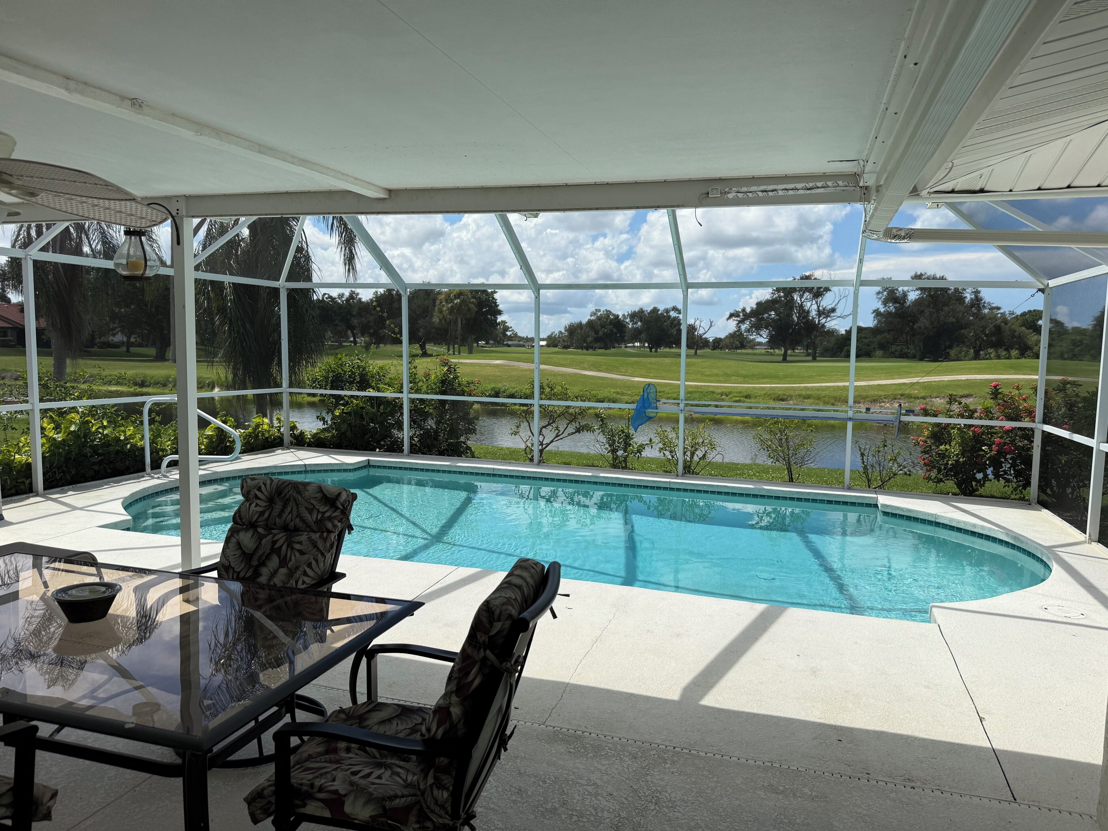 A covered outdoor area with a pool, a table, and chairs.
