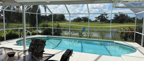A covered outdoor area with a pool, a table, and chairs.