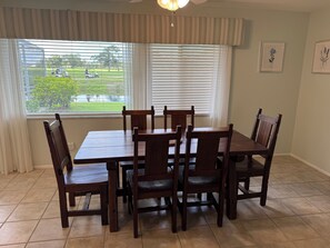 A dining area with a table and chairs, a window with blinds, and a ceiling fan. - Vacation Rental Property by S.Gondola Dr with private swimming pool (Venice)