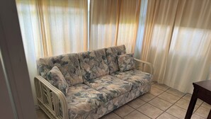 Ein Zimmer mit einer Couch, einem Sessel und Vorhängen.