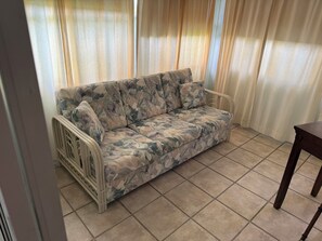 Ein Zimmer mit einer Couch, einem Sessel und Vorhängen.