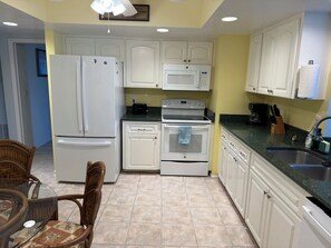 A kitchen with white cabinets, a refrigerator, a microwave, an oven, and a sink. - Vacation Rental Property by S.Gondola Dr with private swimming pool (Venice)