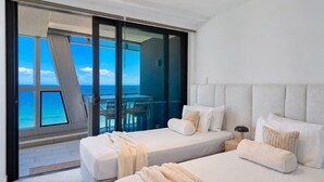 A hotel room with two beds, a view of the ocean, and a balcony with a table and chairs. - Opulence Oceanview 2BR Suite- The Langham + Parking (Surfers Paradise)