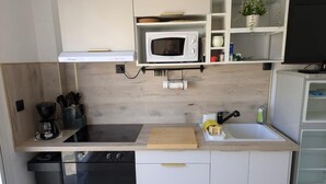 Una cocina compacta equipada con microondas, estufa y lavamanos.