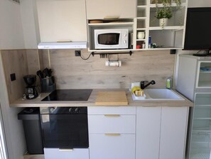 A compact kitchen with a microwave, stove, and sink. - Studio 4 pers Port Cap d'Agde · Plage (Agde)