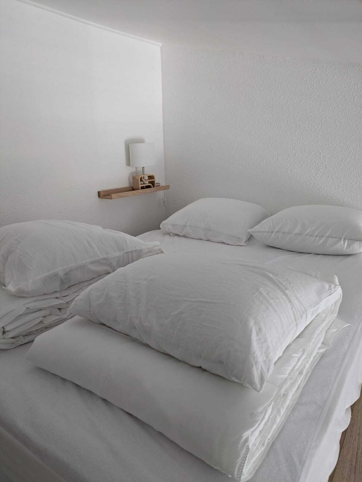 Ein Schlafzimmer mit einem Bett, Kissen, einem Nachttisch und einer Wandlampe.