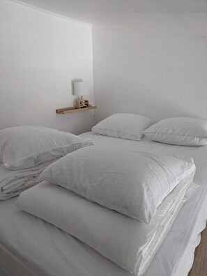 A bedroom with a bed, pillows, a nightstand, and a wall-mounted lamp. - Studio 4 pers Port Cap d'Agde · Plage (Agde)