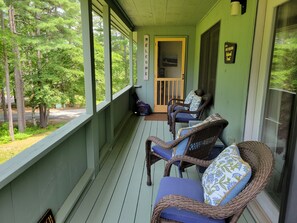 Eine Veranda mit Korbstühlen und einer Tür zu einem Zimmer.