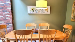 Uma sala de jantar com uma mesa e cadeiras de madeira, um vaso com flores e um quadro na parede.