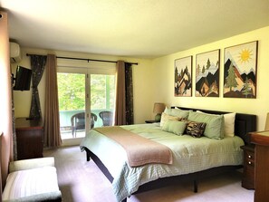 Quarto com cama, cadeira, escrivaninha e varanda com cortinas.
