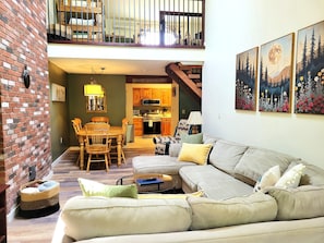 Ein großzügiger Wohnbereich mit einer Couch, einem Esstisch und einer Küche im Hintergrund.