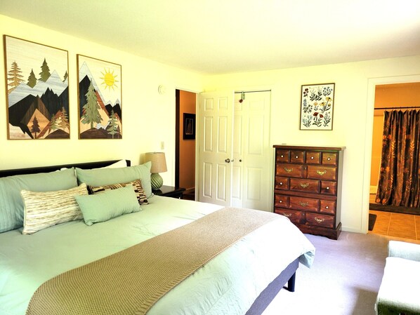 Une chambre à coucher avec un lit, une commode, une porte et des œuvres d’art murales.