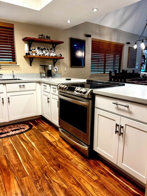 A modern kitchen with white cabinets, a stainless steel stove, and wooden flooring. - Cozy Bear Themed Cabin in Pinetop Country Club (Pinetop Country Club)