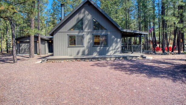 A modern cabin with a large window, a covered porch, and a garage. - Cozy Bear Themed Cabin in Pinetop Country Club (Pinetop Country Club)