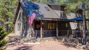 A cabin with a porch, an American flag, and a mountain view. - Cozy Bear Themed Cabin in Pinetop Country Club (Pinetop Country Club)