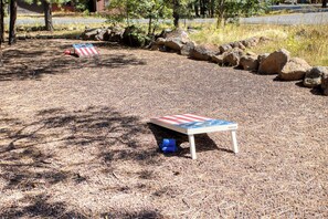 Une petite table en bois ornée d’un motif représentant le drapeau américain, posée sur un sol recouvert d’aiguilles de pin.