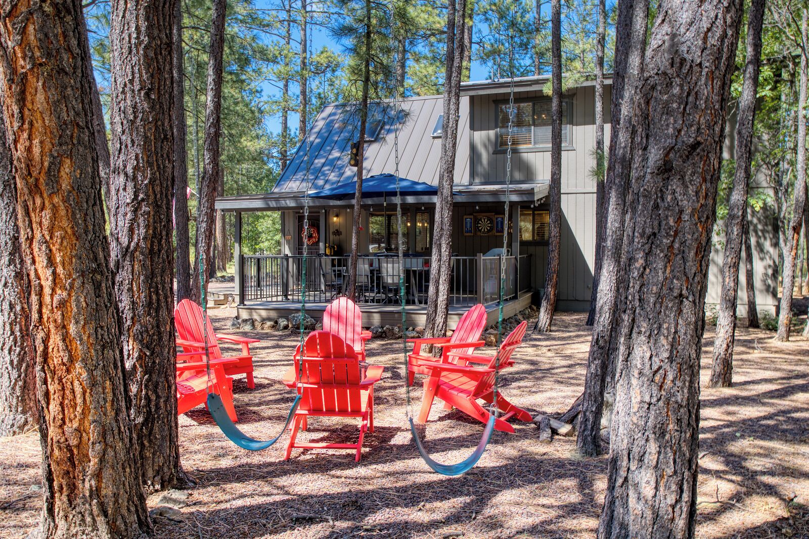 Une cabane dotée d’un porche, de chaises Adirondack rouges et d’une terrasse.