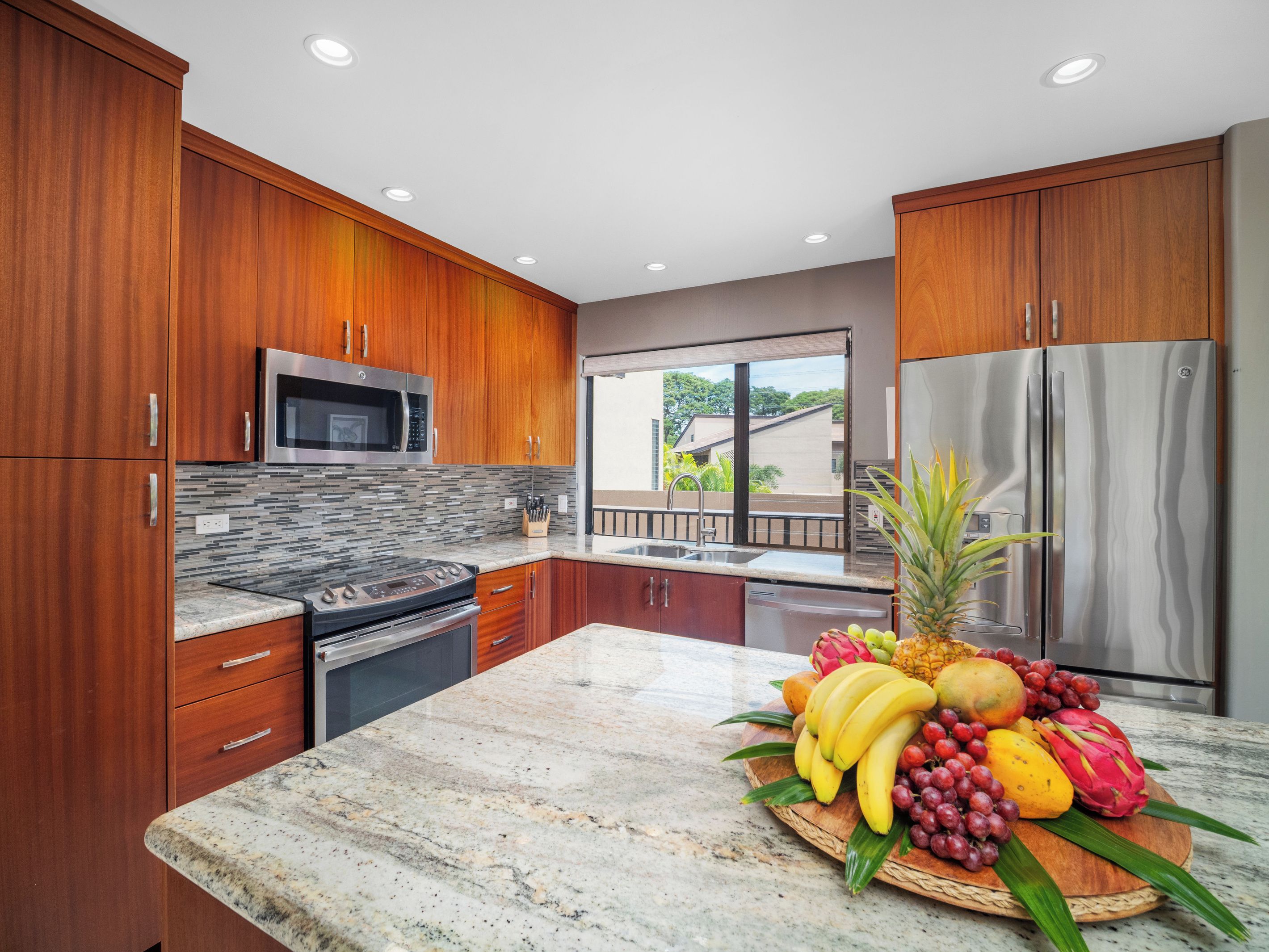A modern kitchen with wooden cabinets, stainless steel appliances, and a marble countertop.