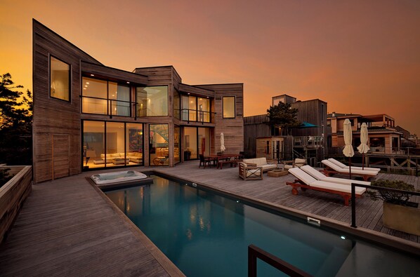 A modern house with a swimming pool, outdoor seating, and a large window overlooking the pool.