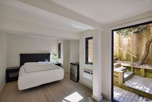 A bedroom with a bed, bedside table, and a window.