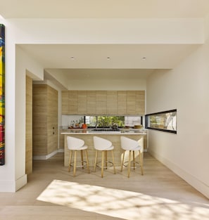 A modern kitchen with wooden cabinets, a central island, and bar stools.